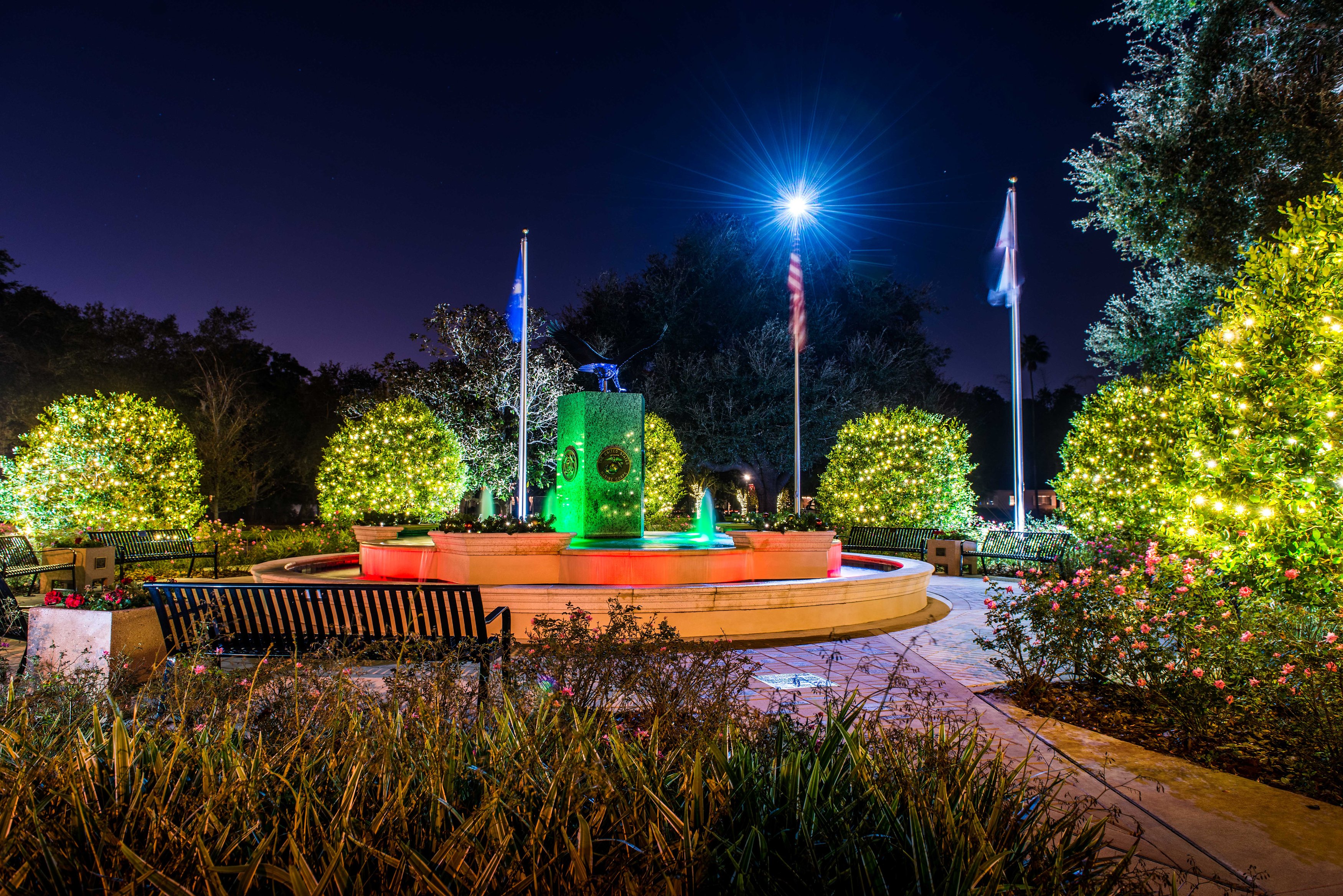 A view of Hunter Memorial Park's fountain, benches, and pavers, lit for the holiday season