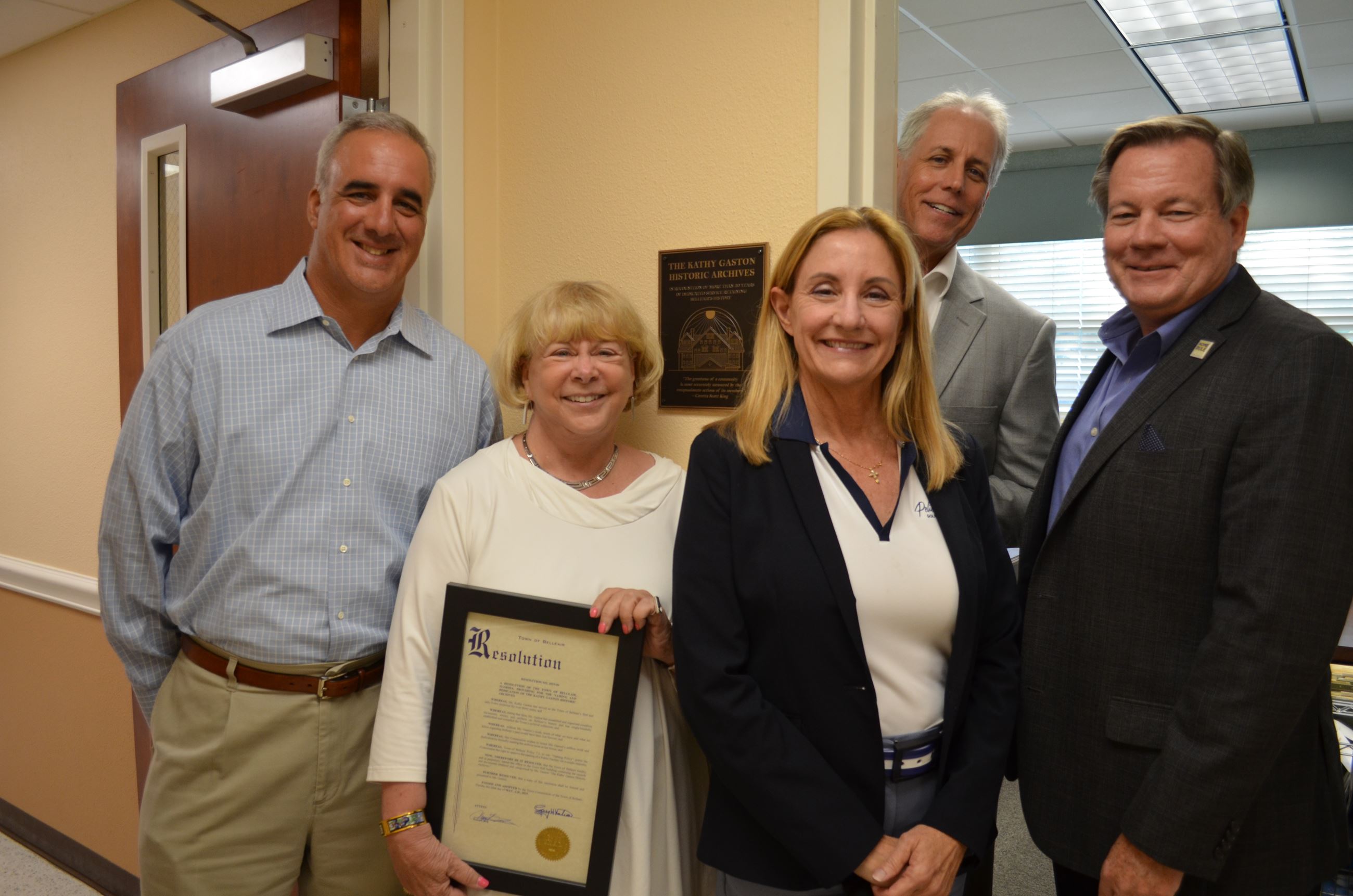 Kathy Gaston and the Town Commission smile proudly in front of the new dedication plaque in Town Hal