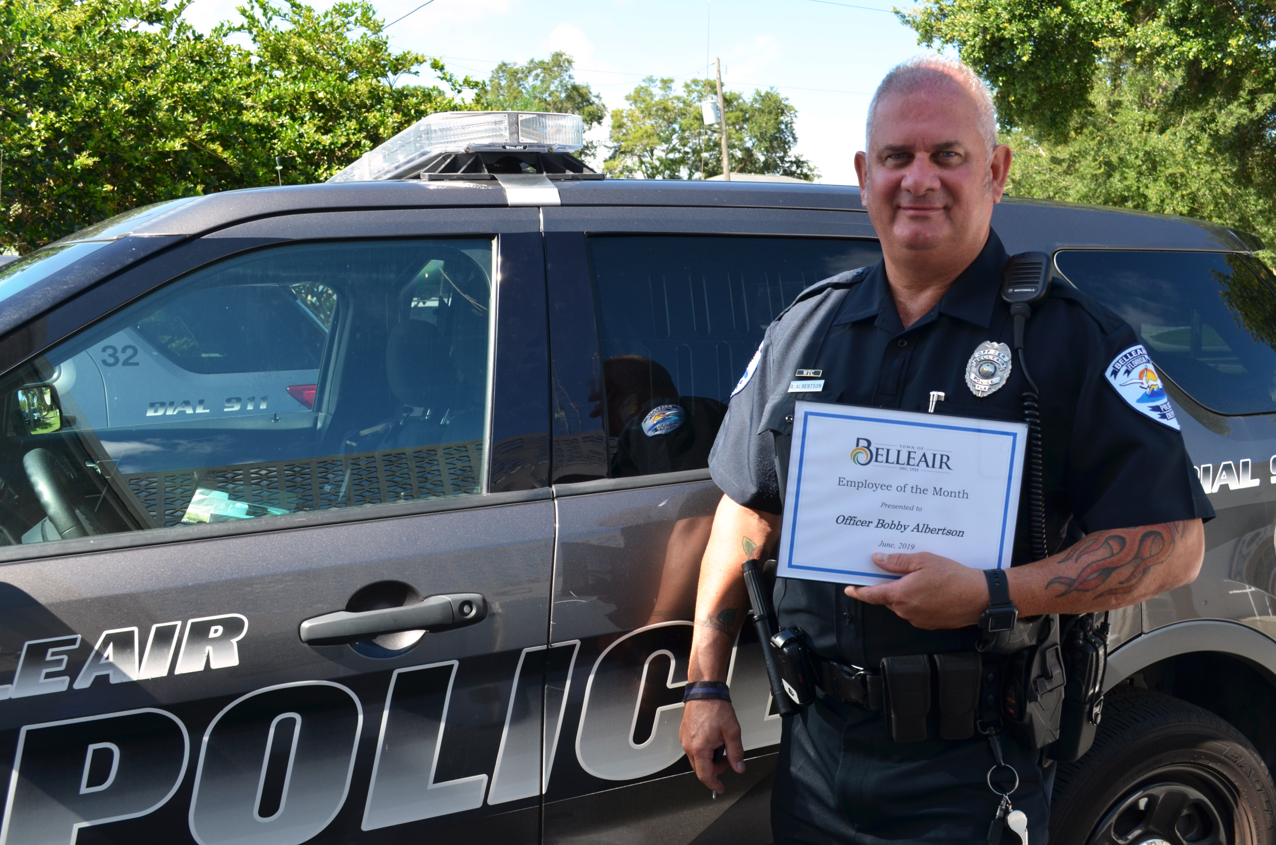 Belleair Police Officer Bobby Albertson stands in front of his squad car holding his Employee of the