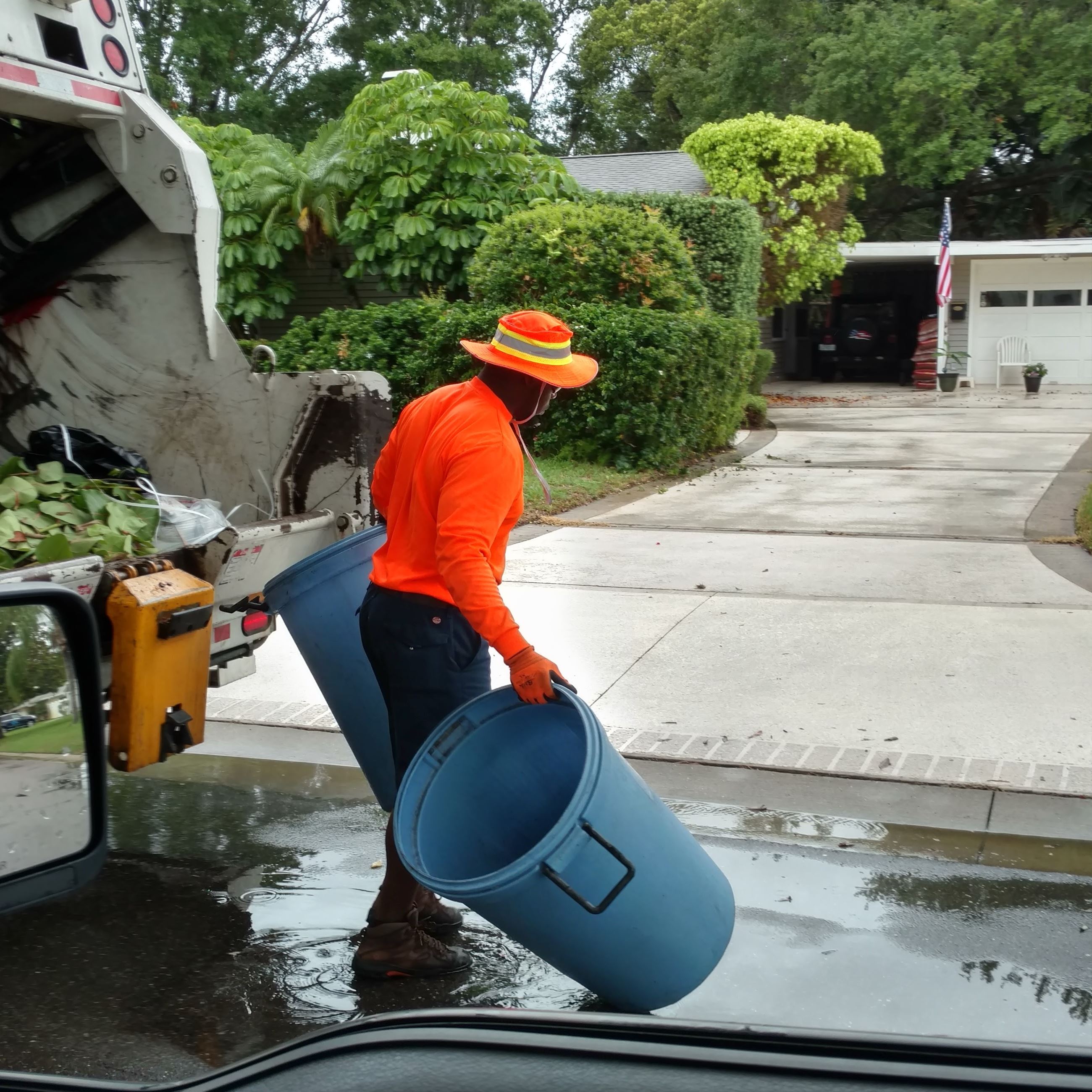 A solid waste employee empties trash into a truck on a rainy day in Belleair