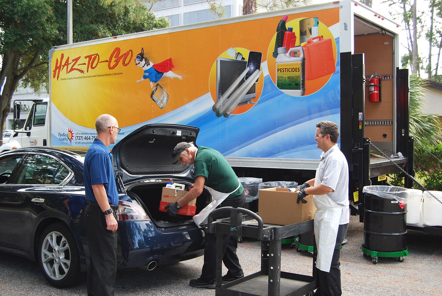 Two Pinellas County employees remove chemicals from the truck of a customer's car