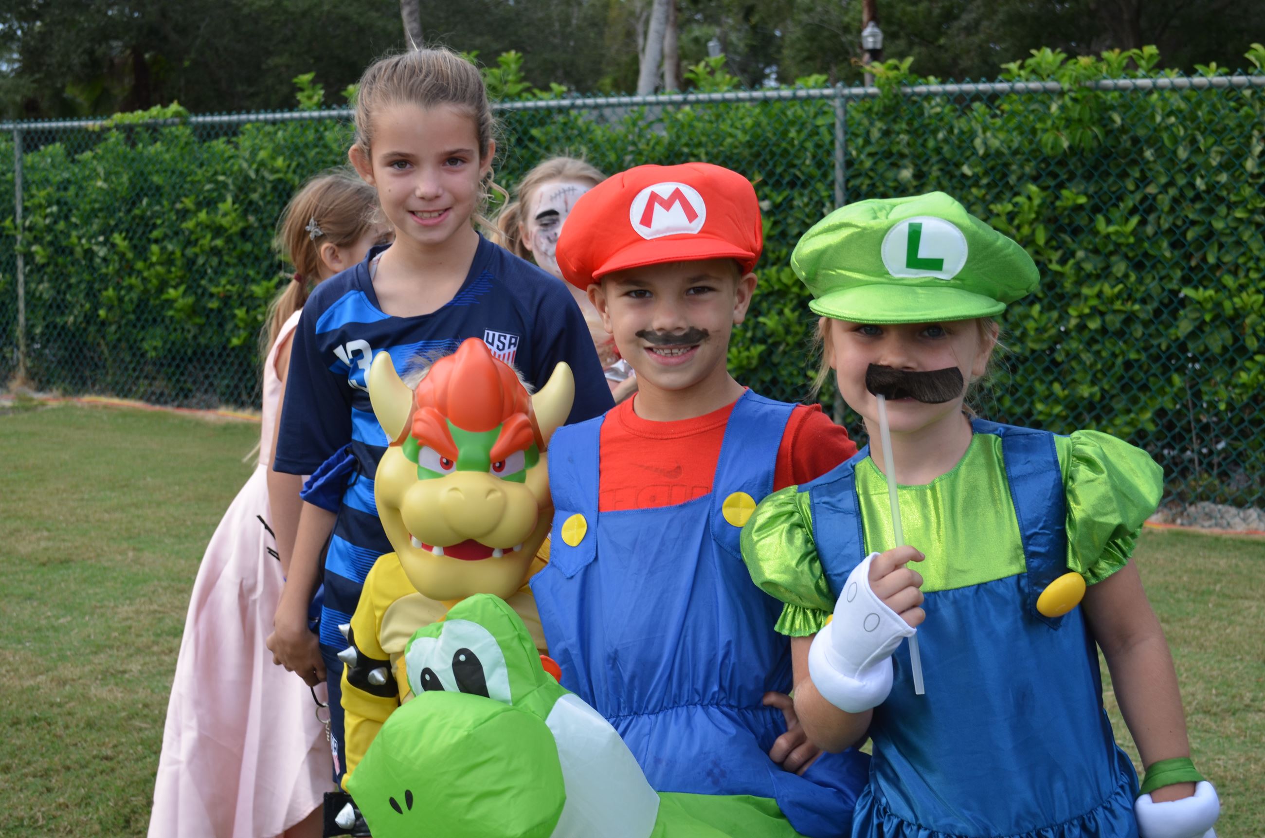 Three children dressed as characters from Nintendo's Mario pose for a photo before the costume co