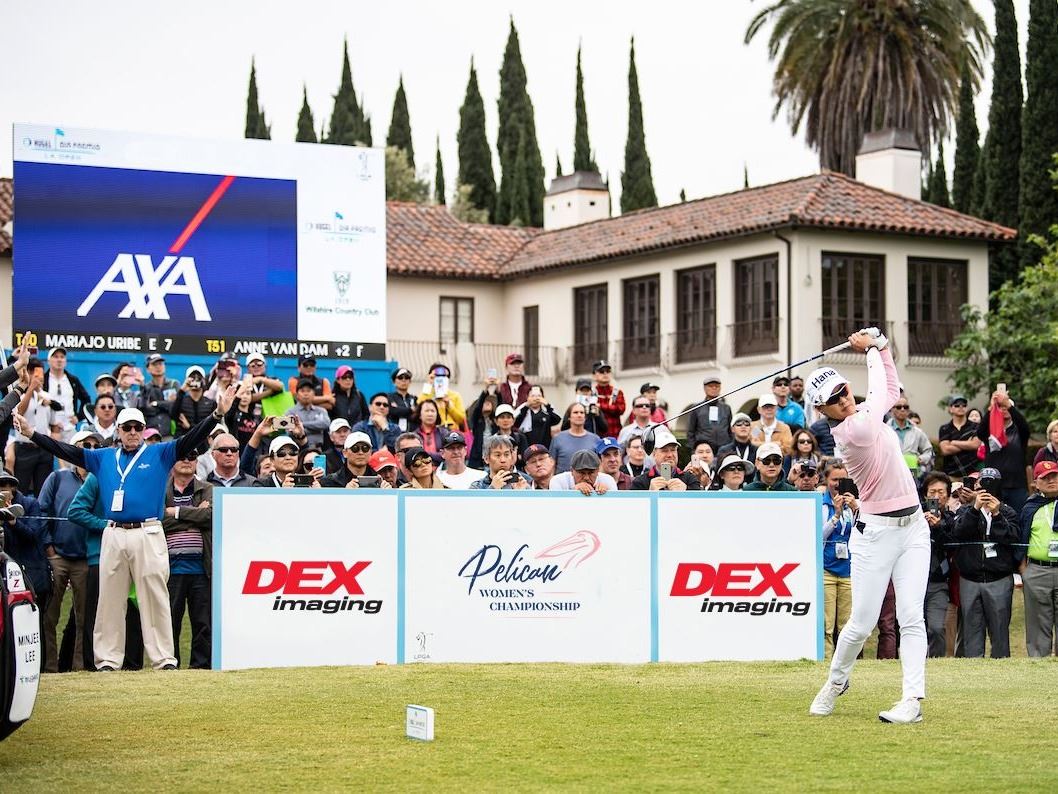 A player at an LPGA tournament tees off in front of a crowd.