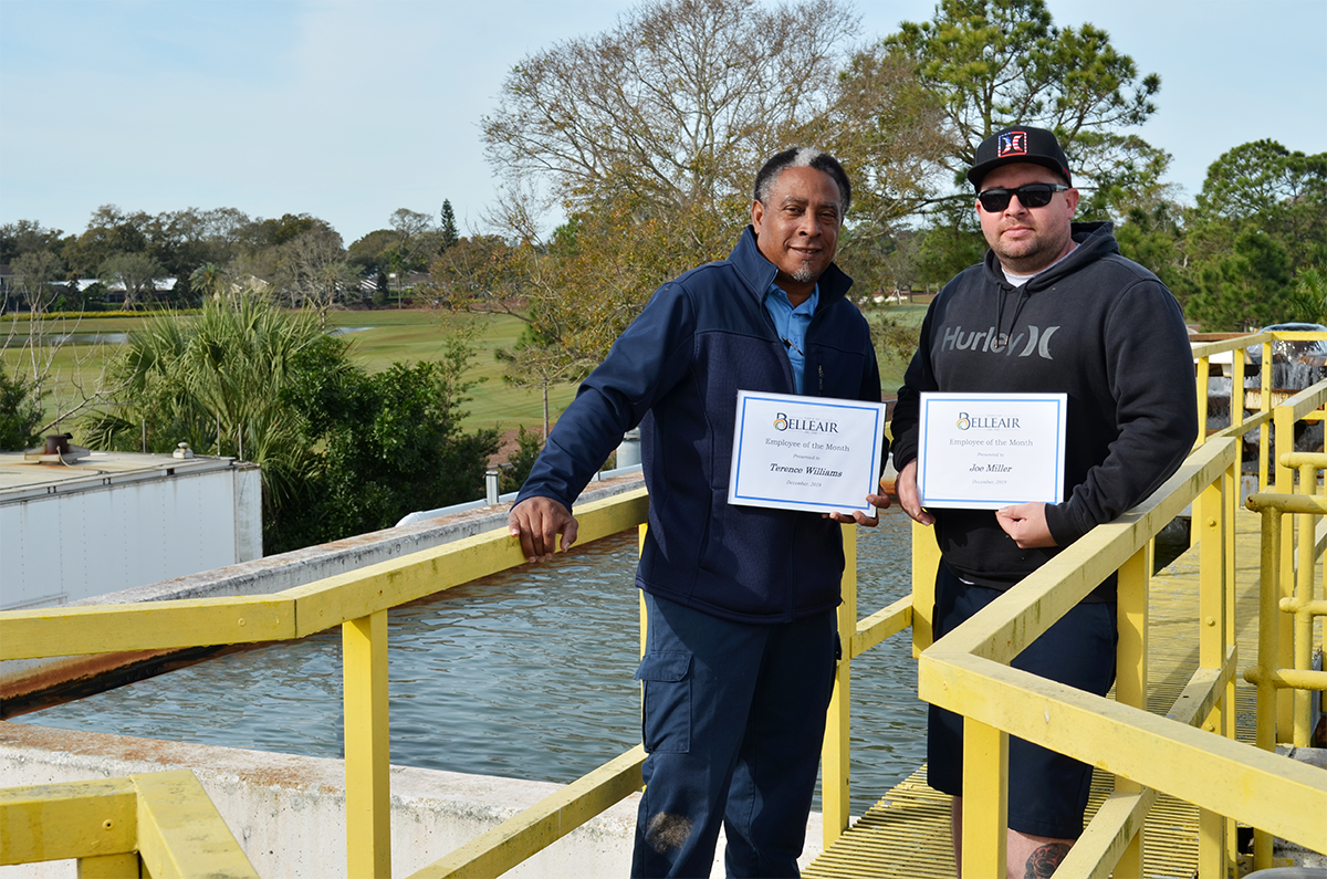 Terry and Joe stand on top of the water treatment plant with their employee of the month certificate