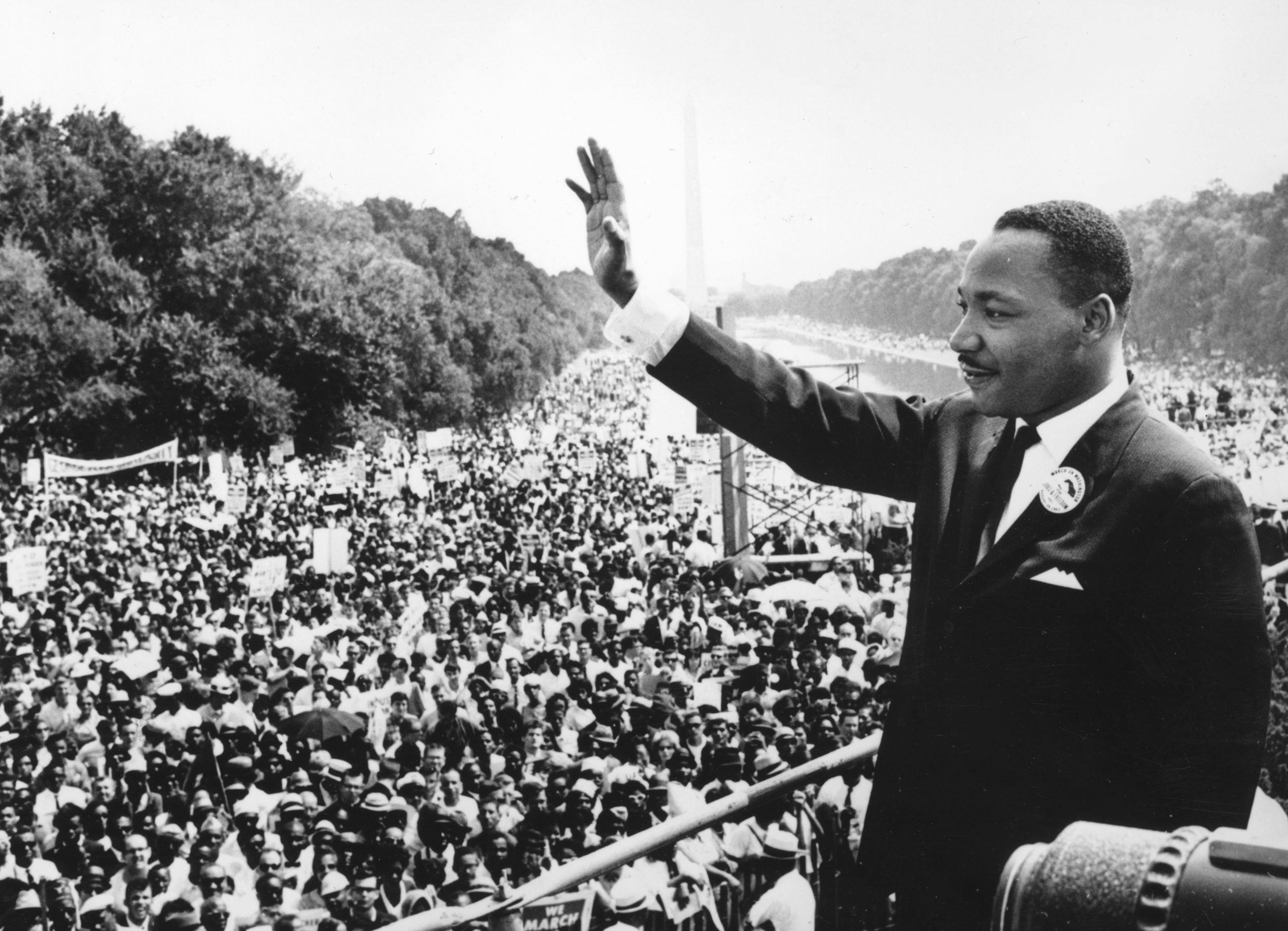 A historic photo of Dr. Martin Luther King Jr. waving in front of a large crowd