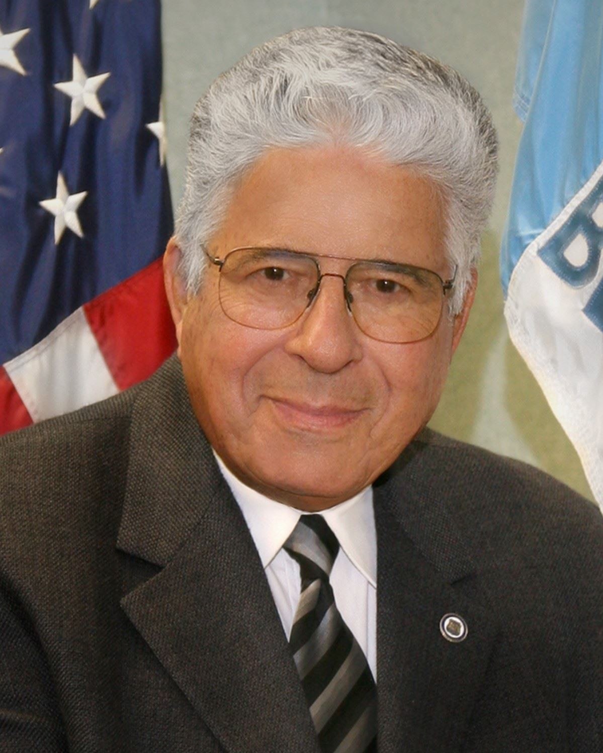 Former Mayor Gary H. Katica smiles in front of an American flag and Belleair's flag.