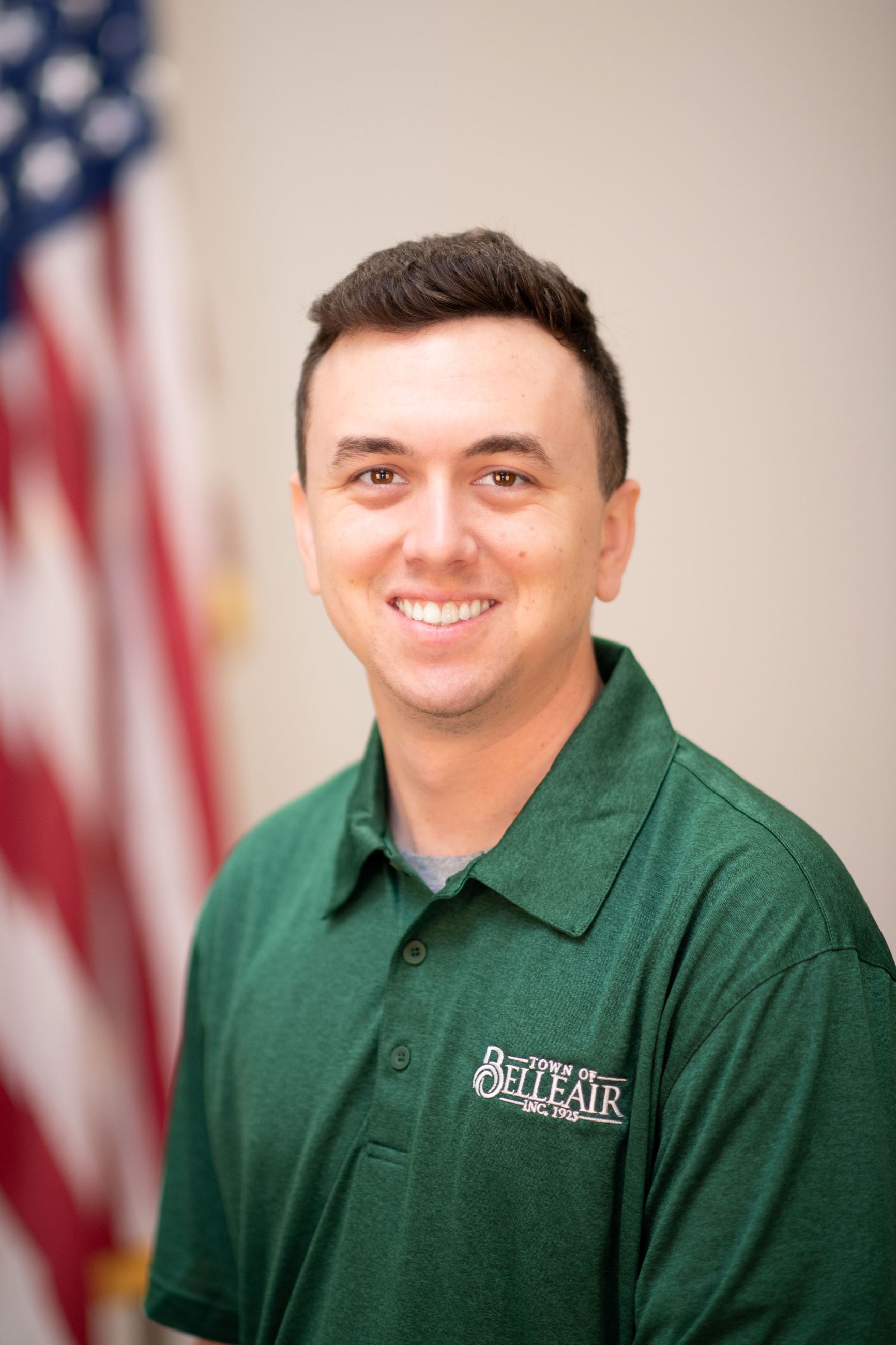 recreation Supervisor, Chris Gray, poses with a smile in front of the American Flag. 